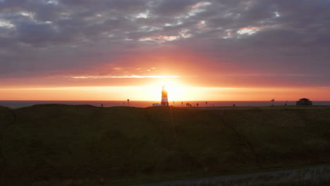 the lighthouse of westkapelle during a bright orange sunset, with a lot of wind