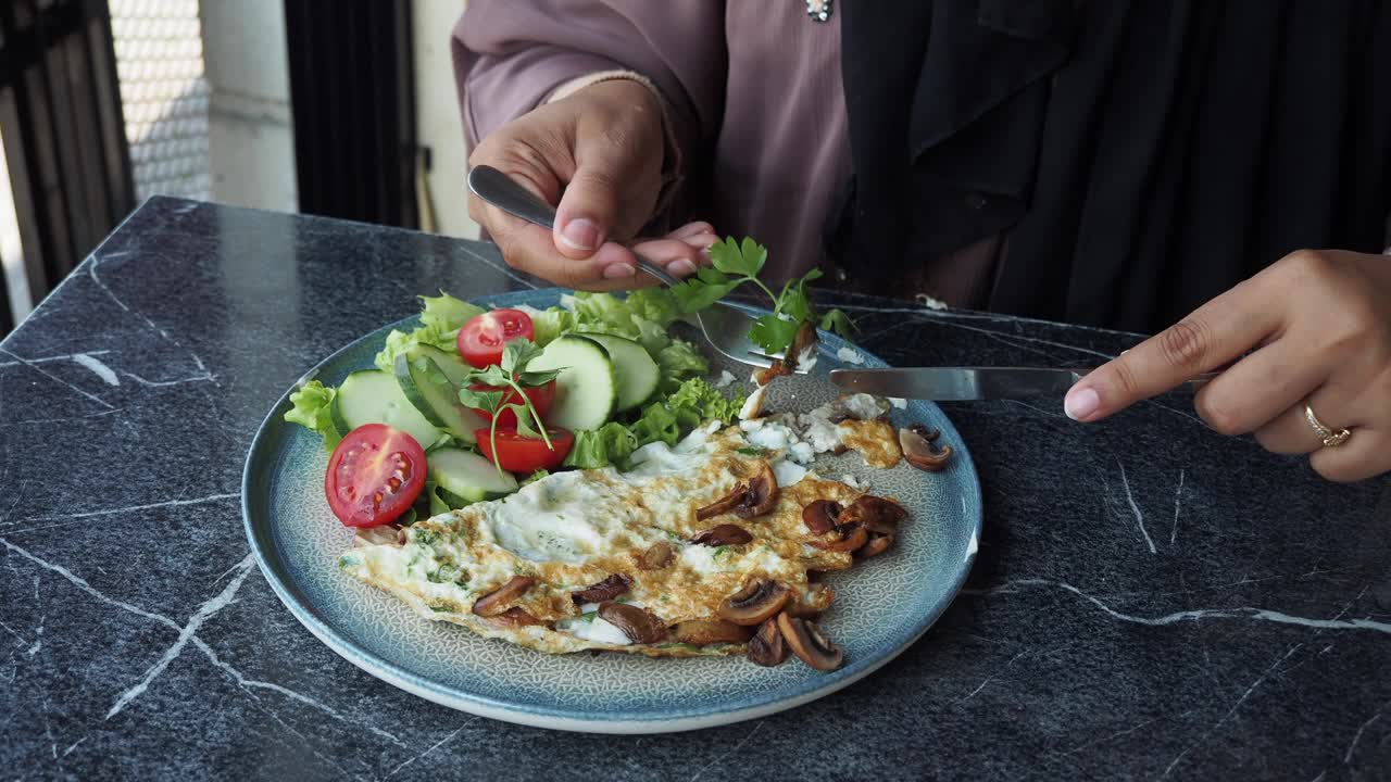 Woman enjoying a healthy breakfast with omelette and salad