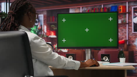 mujer disfrutando de su tiempo libre en casa, usando una computadora de pantalla verde para enviar mensajes de texto a sus amigos