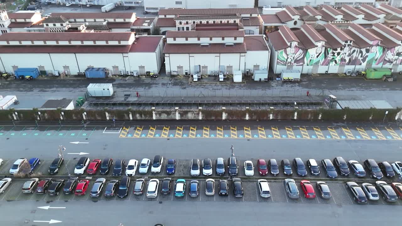 Perspectiva de cima para baixo de um estacionamento, documentando a simetria colorida da infraestrutura de varejo