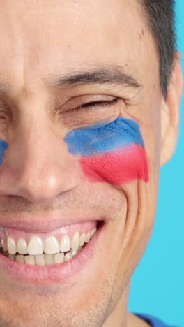 man with a haitian flag painted on the face smiling