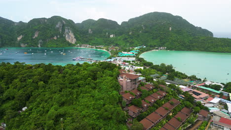Aerial-rising-overview-of-villas-on-hillside-of-koh-phi-phi-to-deep-blue-bay-with-yachts-anchored