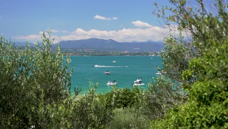 wide establishing shot of boats in the lake with jet ski passing by, on jamaica beach, sirmione, lago garda, lake garda, italy