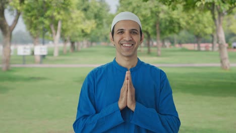 happy muslim man doing namaste in park