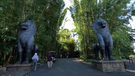 visitantes caminando junto a una gran estatua de león