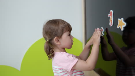 3-year-old-Girl-Toddler-Stick-Different-Animal-Pictures-to-Magnetic-Chalkboard-in-Playroom