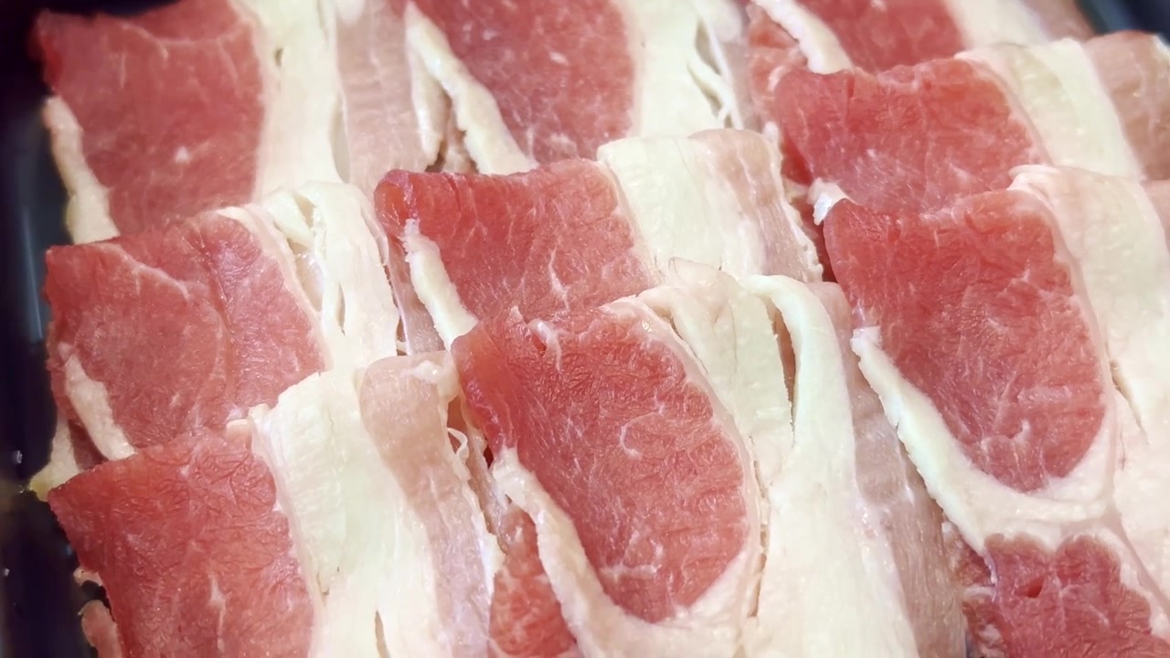 プレミアムな新鮮食材を使用し、すき焼きや鍋物用に準備された薄切り豚肉と牛肉が盛り付けられた皿のクローズアップ。