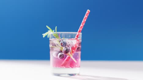 close up of transparent drink with bluberries on blue background