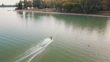 Drone-shot-of-a-person-wake-boarding-on-the-lake-Zlate-Piesky,-Bratislava,-Slovakia,-near-the-shore