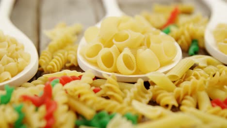 Various-and-colored-pasta-in-spoons-on-wooden-background