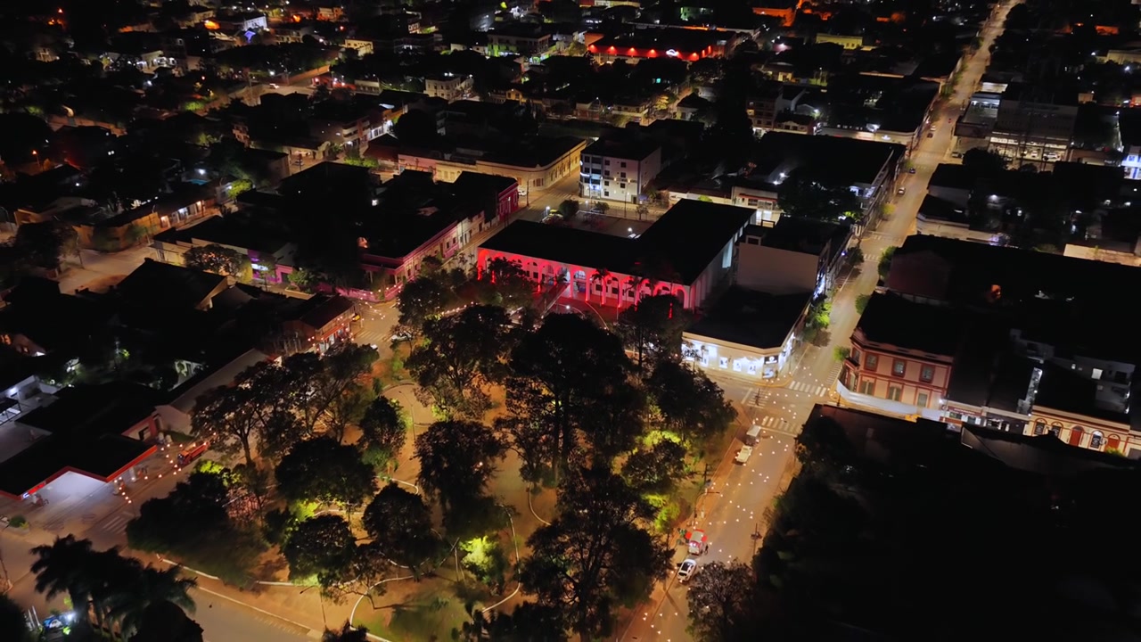 Plaza Libertad con l'edificio della Gobernación del Guairá illuminato di rosso di notte a Villarrica, Paraguay. Ripresa aerea con allontanamento e ascesa.