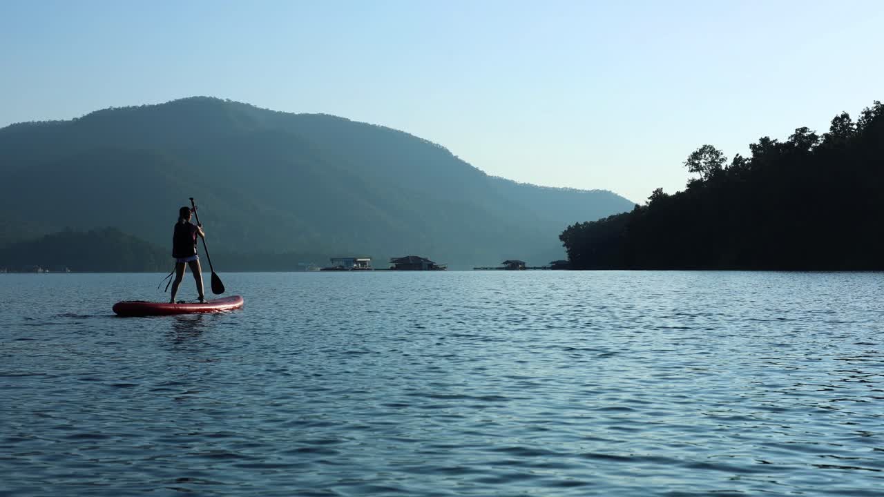 persona que hace paddleboard en aguas tranquilas al anochecer