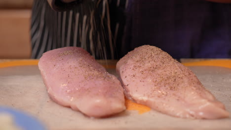 salpicar pechugas de pollo deshuesadas y sin piel con un molinillo para prepararlas para cocinarlas