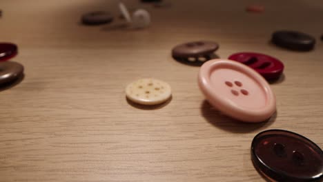 los botones de coser caen sobre un fondo de madera. la ropa los botones coloridos caen sobre la tabla de madera
