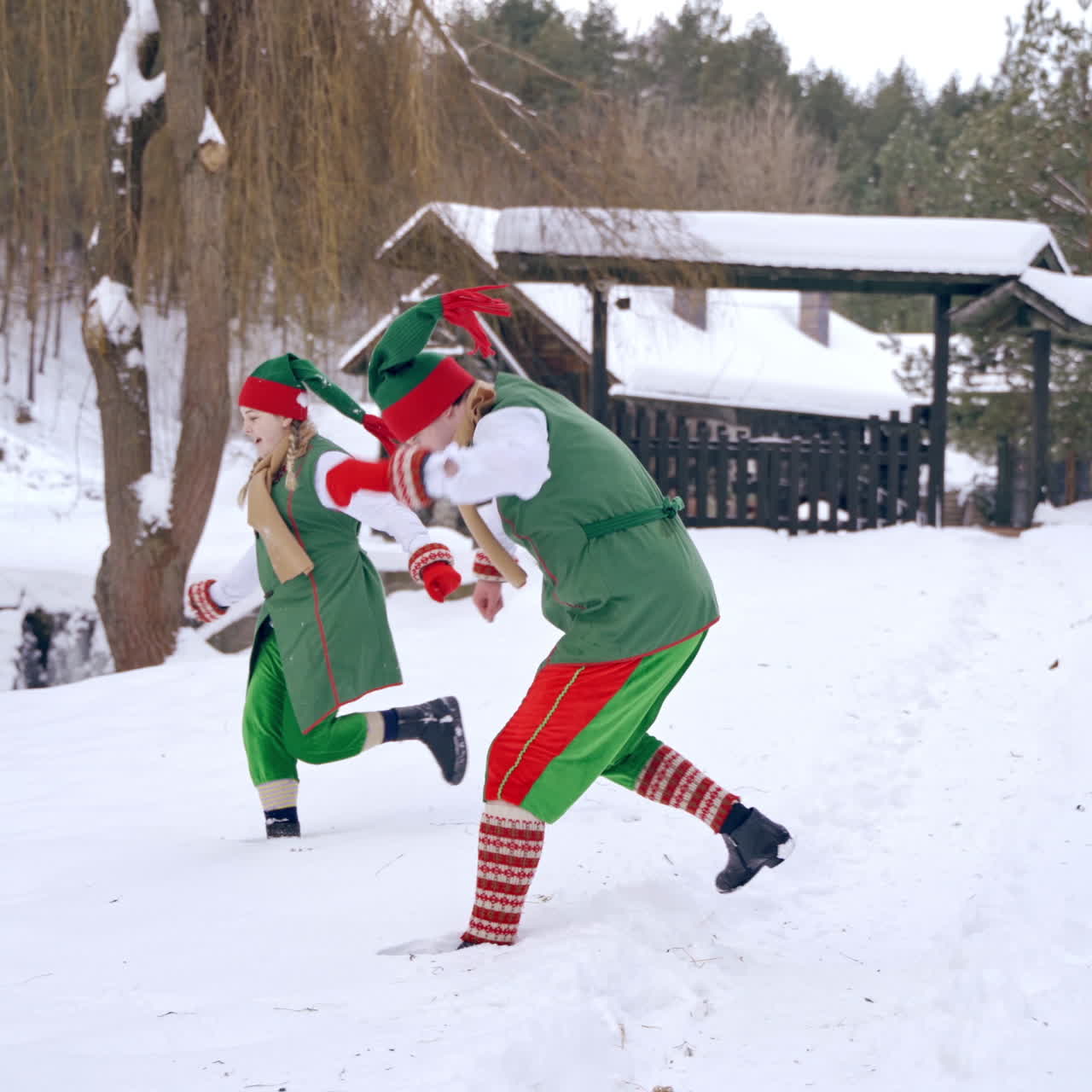 Couple of elves are playing snowballs running aroud a backyard. Holidays. Christmas eve. New year is coming. Winter landscape