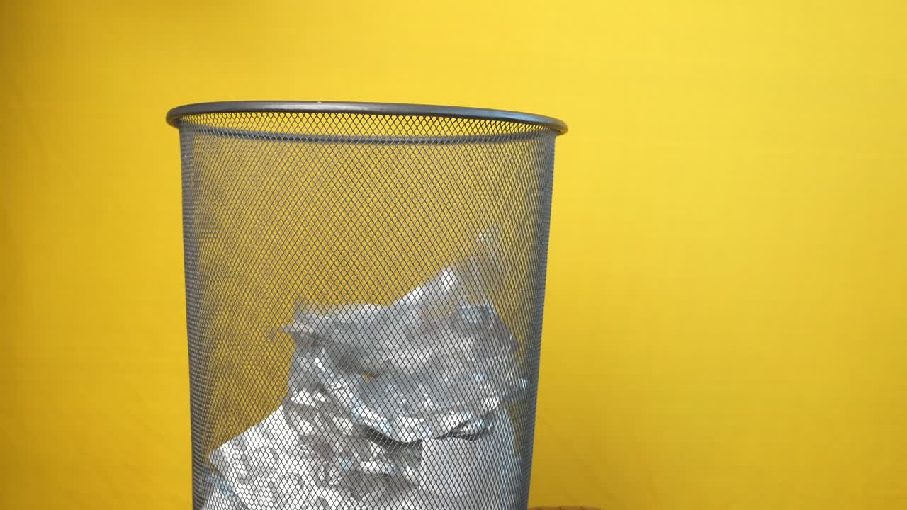 노란색 배경 에 인 종이 로 가득 찬 금속 쓰레기통