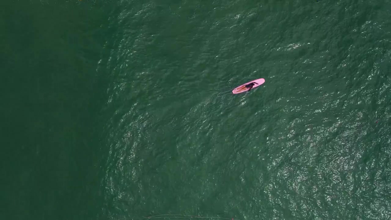 A Woman Swimming In The Water, Lying On A Surfboard In Da Nang Beach, Vietnam. Aerial Shot