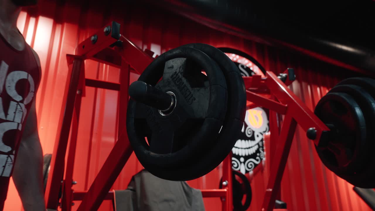 잘생기고 근육질의 젊은 남자가 바벨의 무게를 바꾸고 있는 웨이트 트레이닝 기계의 클로즈업