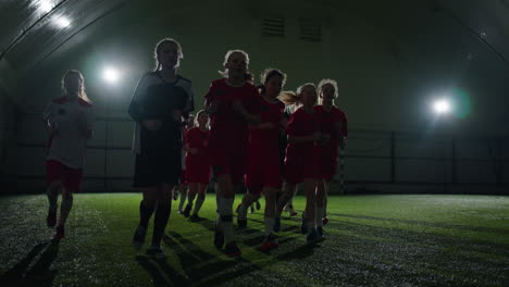 young female soccer players running on an indoor field