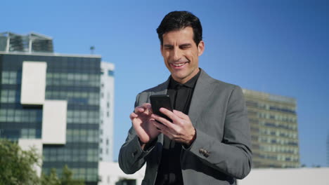 Businessman-reading-good-news-on-phone-at-street