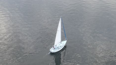 sailing ship in the middle of ocean with reflections on water - aerial drone shot