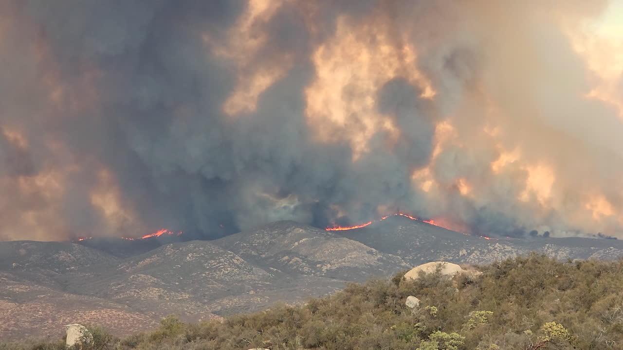Veduta a lunga distanza di un incendio sulle pendici di una collina.