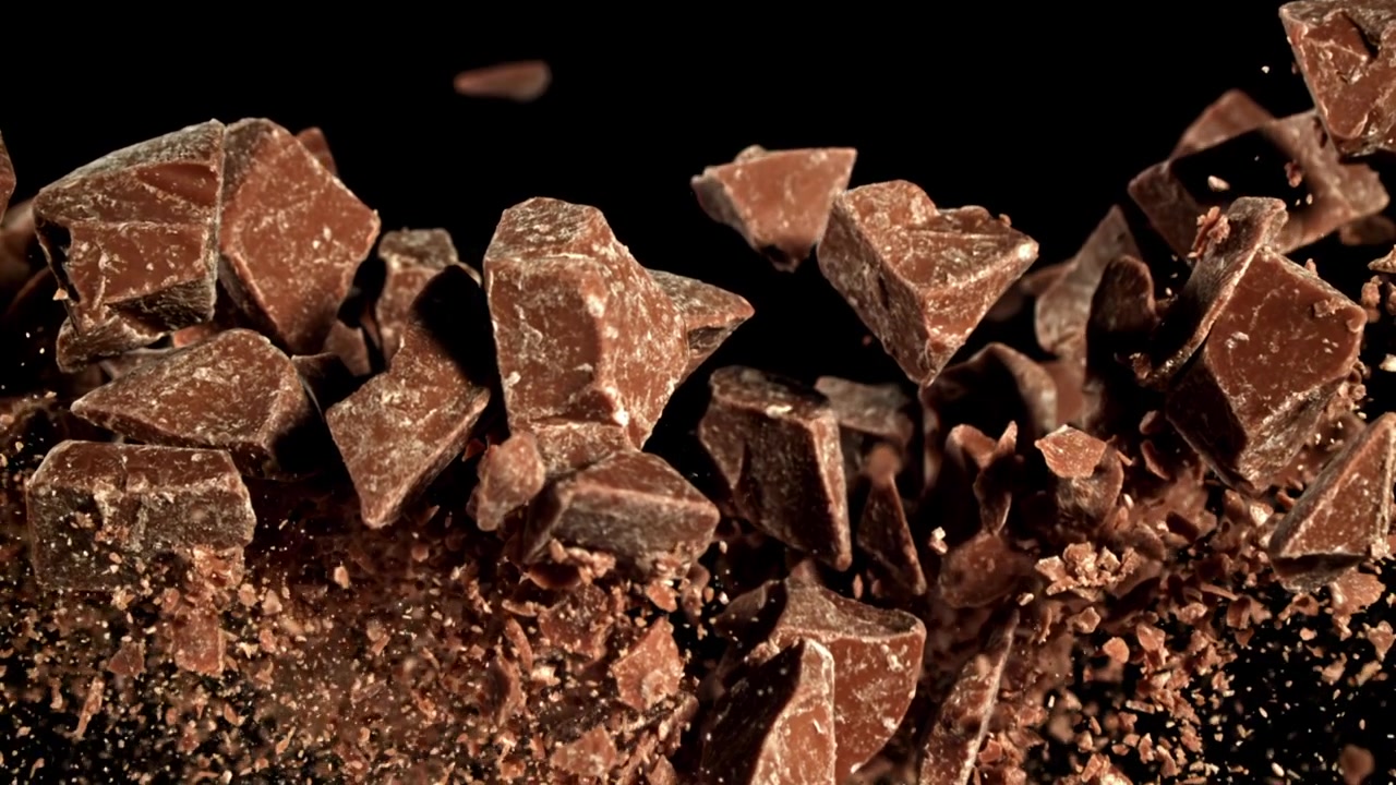 Pezzi e briciole di cioccolato che cadono e si accumulano su sfondo nero