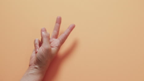 cerca de la mano de una mujer cacauana que muestra un signo de paz con espacio de copia en un fondo amarillo