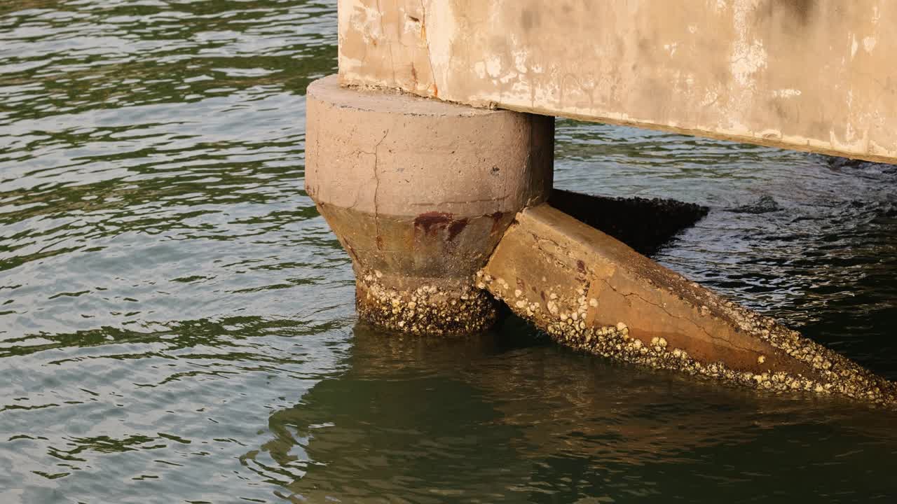 Concrete pier structure with barnacles in water