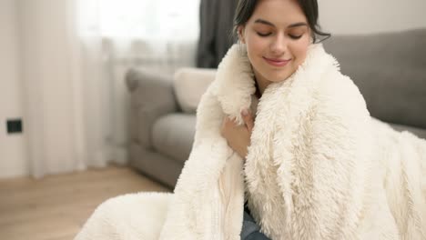 Portrait-of-young-beautiful-woman-in-warm-fur-blanket-at-home