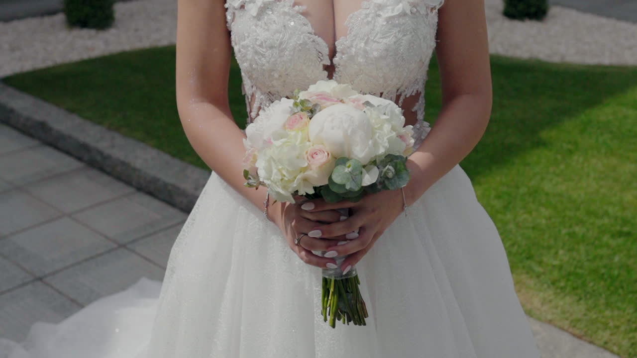 novia en un vestido de novia de encaje blanco sosteniendo un ramo de flores blancas y rosas