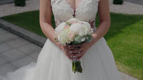 bride in a white lace wedding gown holding a bouquet of white and pink flowers