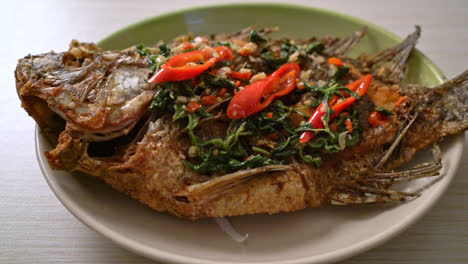 fried tilapia fish with basil chili garlic sauce on top - homemade food style