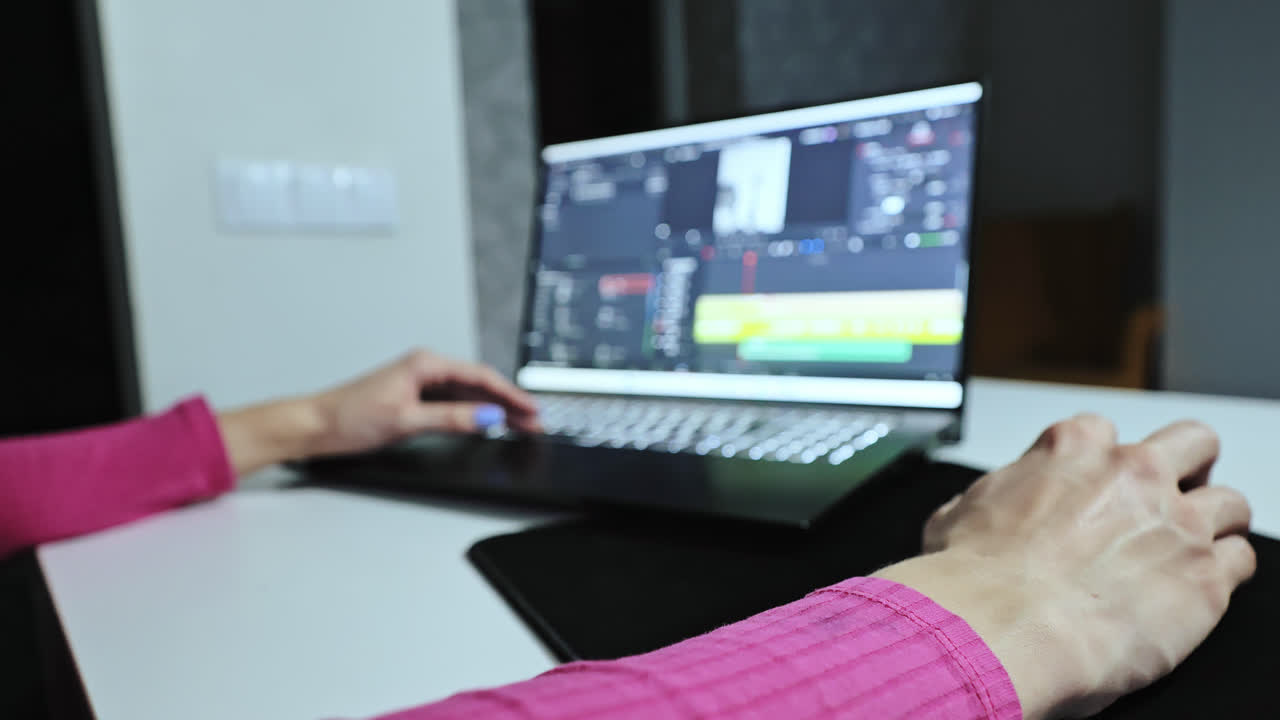 Woman in pink works from home editing content for digital media campaigns