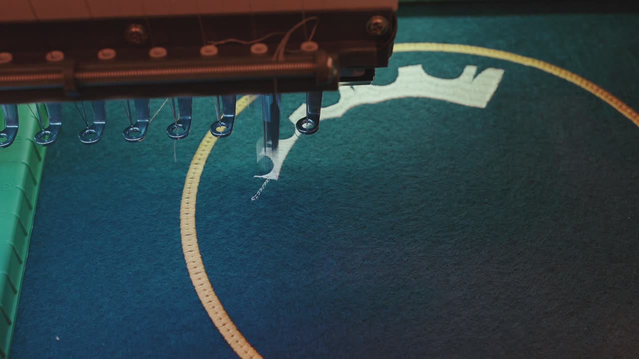 automatic embroidery machine working on blue textile in detail view