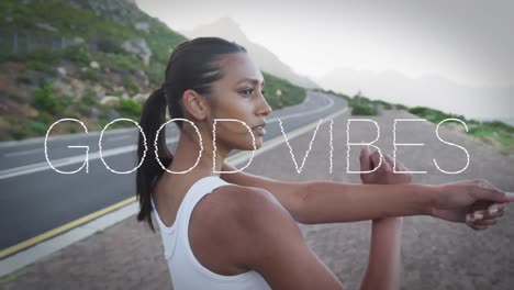Animation-of-the-words-good-vibes-written-in-white-over-woman-exercising-on-mountains-road