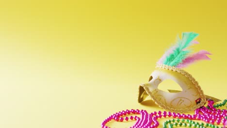 Video-Einer-Maskerademaske-Mit-Federn-Und-Mardi-Gras-Perlen-Auf-Gelbem-Hintergrund-Mit-Kopierraum