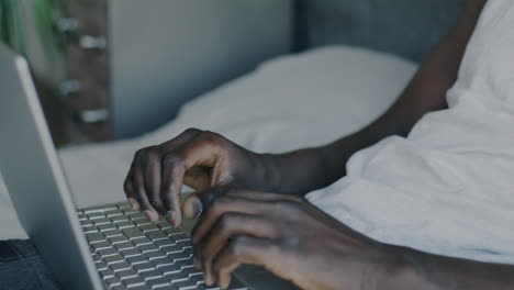 man working on laptop in bed