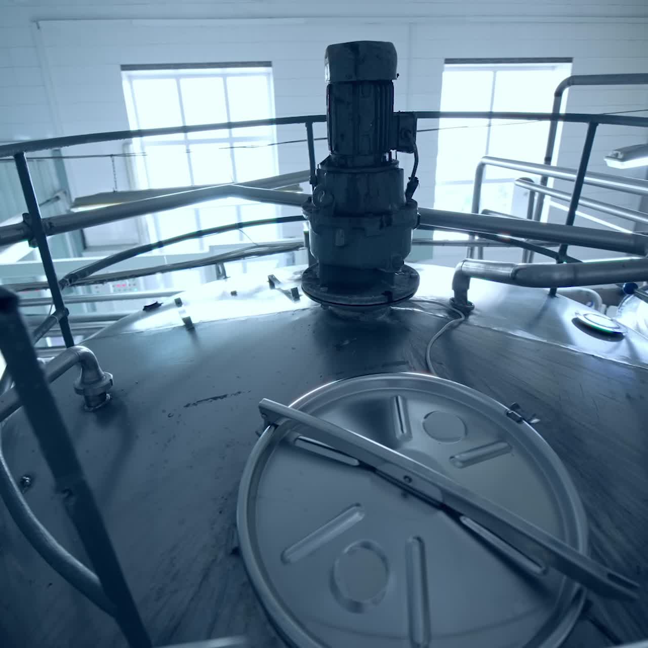 Big steel tanks standing in a row at the dairy plant. The look at the tops of milk cisterns from above. Gaze from a bridge leading to the cistern lids