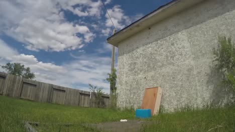 TIME-LAPSE---In-the-yard-from-the-side-of-a-house-as-the-clouds-fly-over-ahead-on-a-sunny-cloudy-day-creating-shadows-across-the-yard