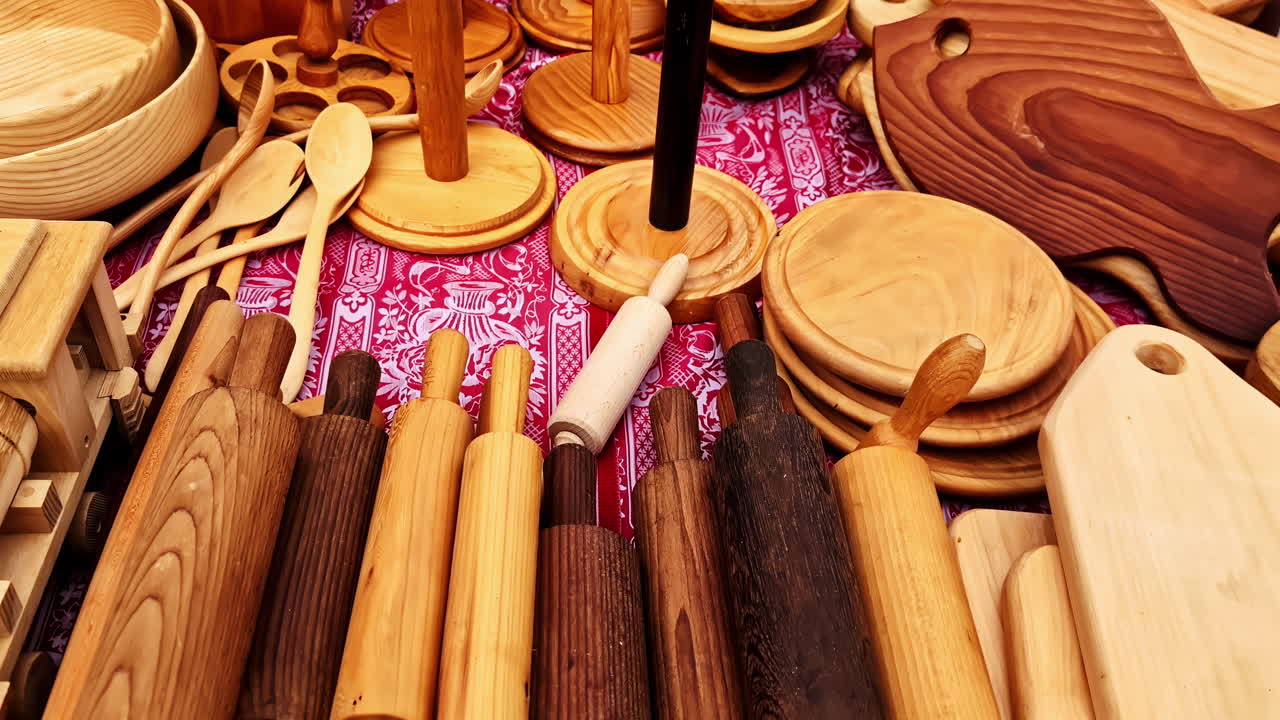 Wooden kitchen utensils, including rolling pins, bowls, and spoons, displayed in a market