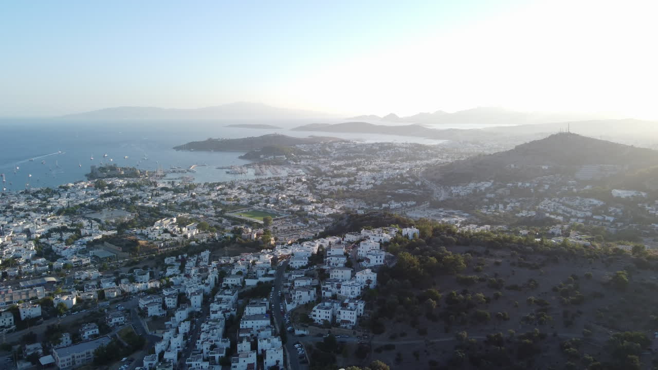 un avión volando hacia atrás sobre los edificios blancos de bodrum al amanecer, turquía