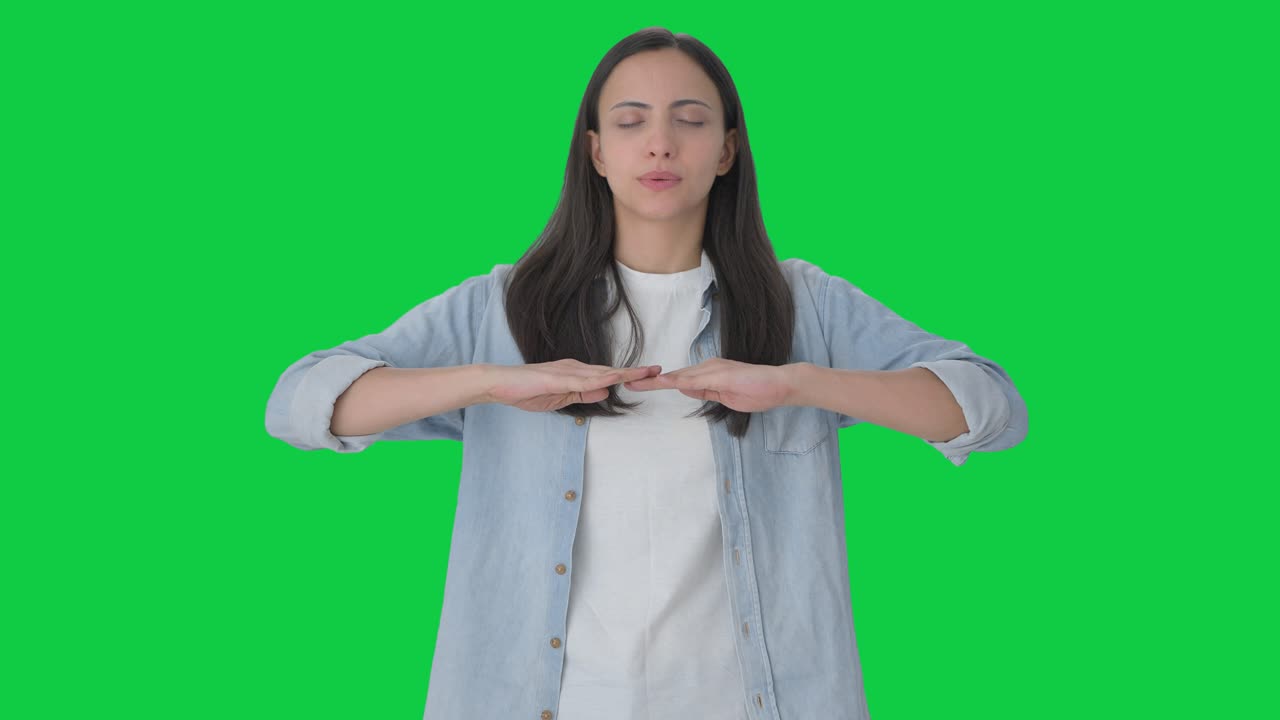 인디언 소녀는 숨을 들이마시고 숨을 내쉬고 운동을 합니다. 녹색 화면