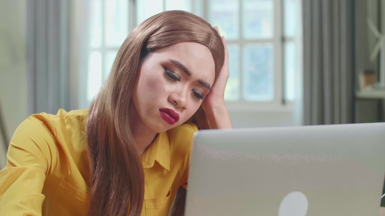 Bored Asian Young Transgender Woman Working With Laptop Computer In Living Room