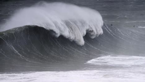 Riesige-Welle-Bei-Nazaré-Bricht-Und-Gibt-Den-Blick-Auf-Jetski-Fahrer-Dahinter-Frei,-Zeitlupe-4K