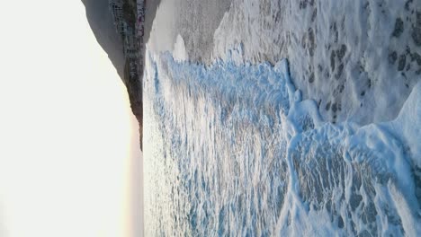 disparo aéreo de olas que se estrellan en la orilla de una playa de arena al anochecer