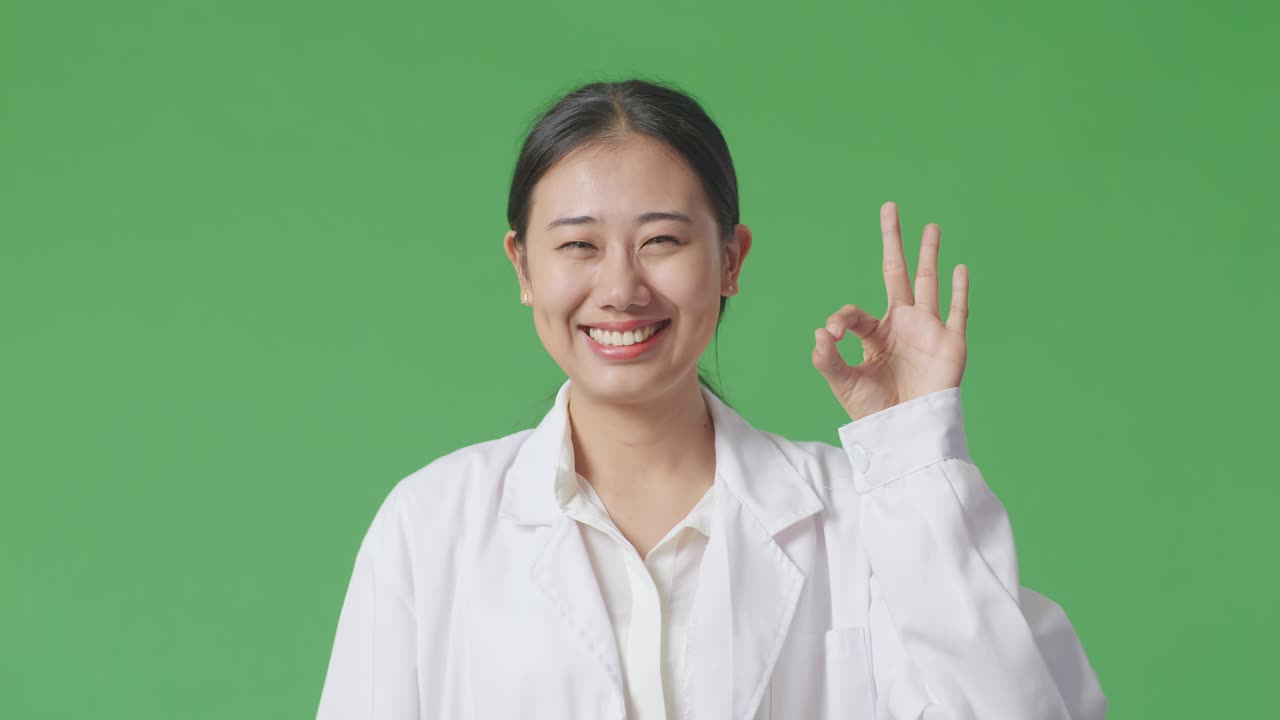 코트 를 입은 여자 가 ok 표지 를 하고 있다