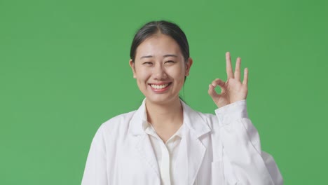 코트 를 입은 여자 가 ok 표지 를 하고 있다