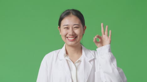 woman in white coat making ok sign