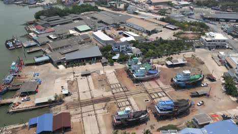 aerial view of a busy boat repair yard and shipyard with various vessels in dry dock and docked along a river